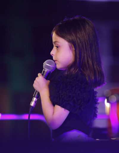 Bambina che canta al microfono durante una performance dal vivo ad ArteMusica Piacenza