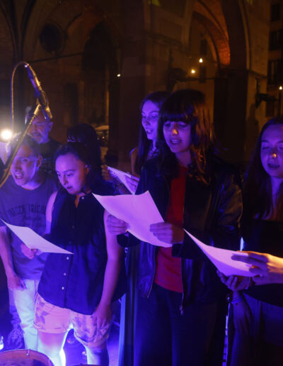 Studenti e insegnante cantano insieme sul palco durante un concerto serale di ArteMusica Piacenza 2023/24