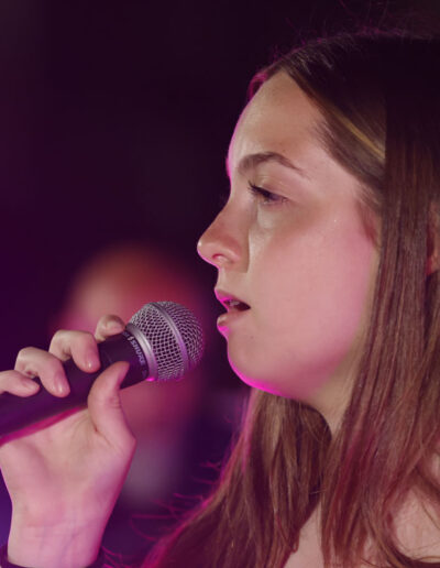 Giovane cantante durante un'esibizione live di ArteMusica Piacenza, ripresa in primo piano con microfono