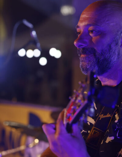Chitarrista durante un’esibizione live, illuminato dalle luci di scena, stagione 2023/24 di ArteMusica Piacenza