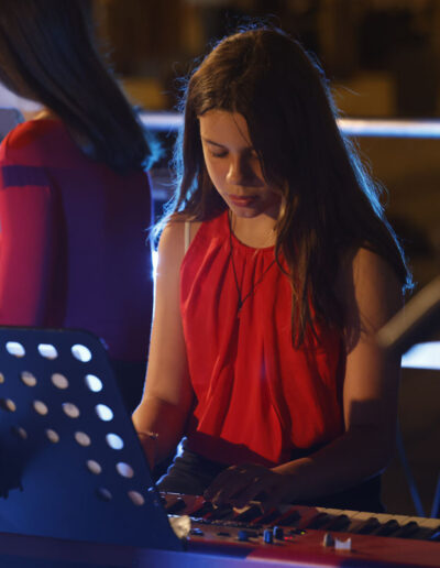 Giovane studentessa di ArteMusica Piacenza che suona la tastiera durante un’esibizione serale