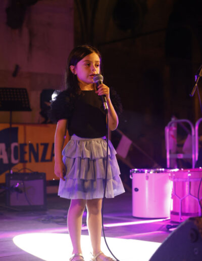 Bambina che canta al microfono durante un’esibizione dal vivo sul palco