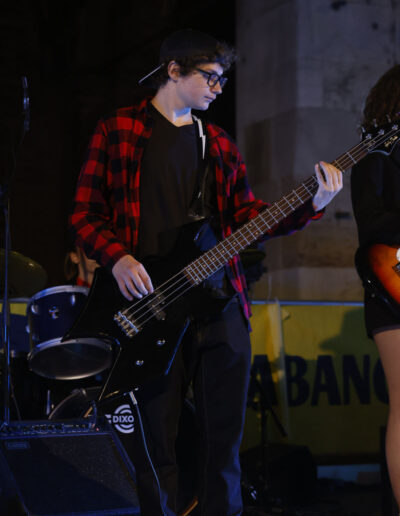 Giovane bassista che suona dal vivo durante un concerto serale