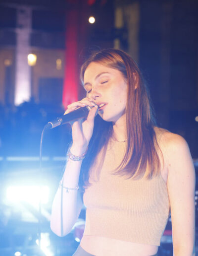 Giovane cantante di ArteMusica Piacenza che canta dal vivo con microfono sul palco