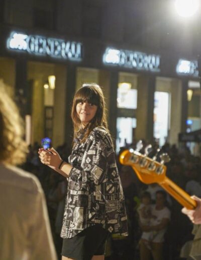 Giovane cantante sul palco durante un concerto a Piacenza insieme a due musicisti