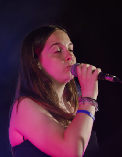 Giovane cantante che si esibisce al microfono durante uno spettacolo musicale