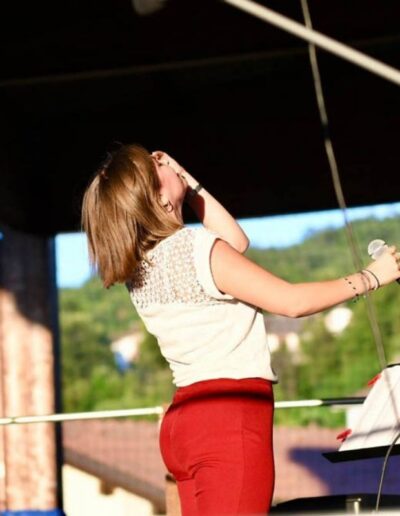 Giovane cantante sul palco mentre prova la voce con il microfono durante un evento all’aperto