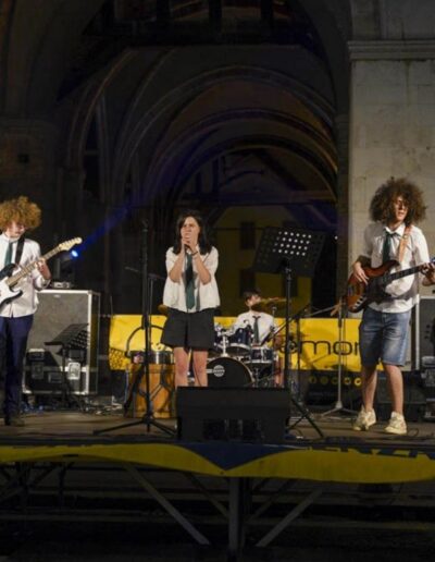 Band di giovani musicisti si esibisce dal vivo al Palazzo Gotico durante un concerto serale
