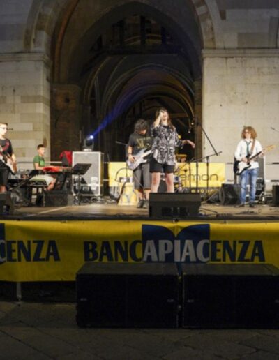 Giovani musicisti sul palco durante un evento musicale sponsorizzato da Banca di Piacenza