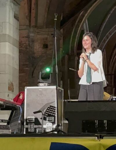 Cantante e pianista sorridono sul palco durante un concerto sotto i portici di Piacenza