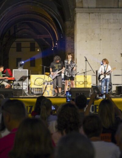 Gruppo di giovani musicisti si esibisce sul palco durante un evento serale a Piacenza davanti al pubblico