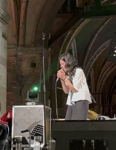 Cantante e pianista si esibiscono dal vivo sotto i portici di Piacenza durante un concerto serale