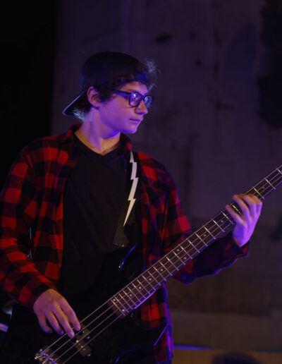 Giovane bassista suona dal vivo durante un concerto a Piacenza