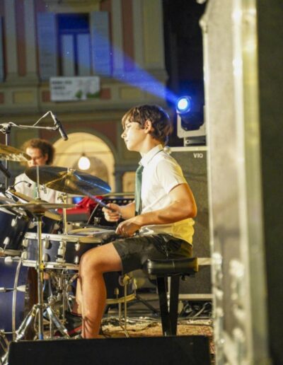 Giovane batterista suona la batteria durante un concerto serale in Piazza Cavalli a Piacenza.