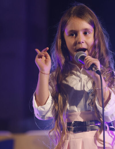 Bambina che canta al microfono durante un’esibizione live
