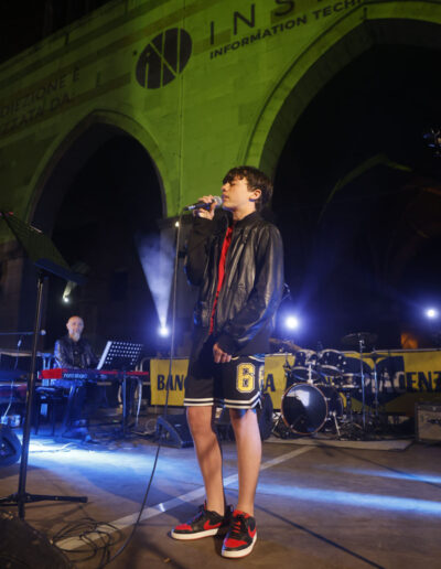 Giovane cantante che si esibisce sul palco durante un concerto serale a Piacenza