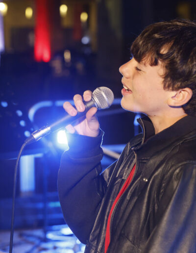 Giovane cantante di ArteMusica Piacenza che canta dal vivo sul palco tenendo il microfono