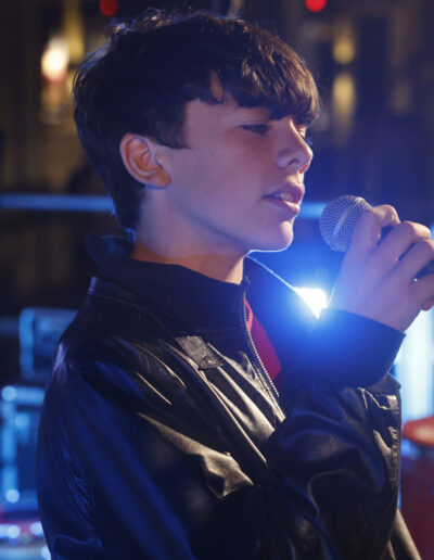 Giovane cantante di ArteMusica Piacenza che canta dal vivo tenendo il microfono sul palco