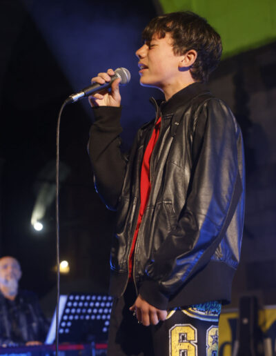 Giovane cantante che si esibisce dal vivo sul palco durante un concerto serale