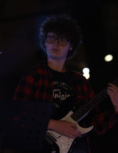 Giovane chitarrista elettrico si esibisce dal vivo durante un concerto serale