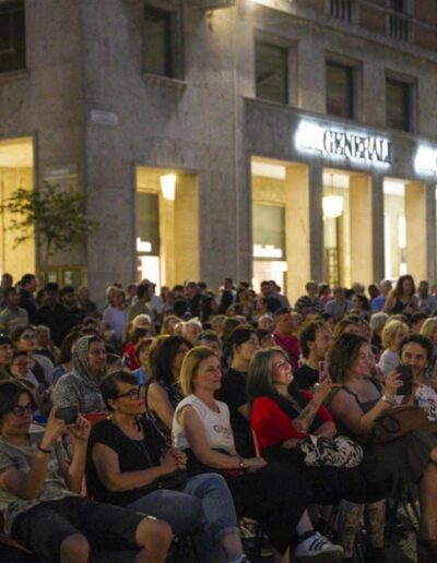 Grande pubblico seduto e in piedi durante un evento musicale serale a Piacenza
